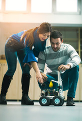 Young students of robotics preparing robot for testing in workshop