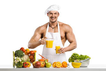 Man bodybuilder cook, cooking freshly squeezed juice and vegetables salad