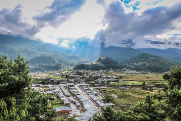 Sunrays leaking from  clouds over peaceful village in Bumthang valley, Bhutan.