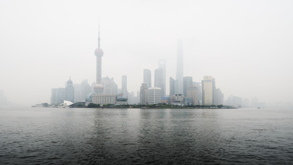 View of Shanghai business district skyline across the Huangpu river, with pollution mist.