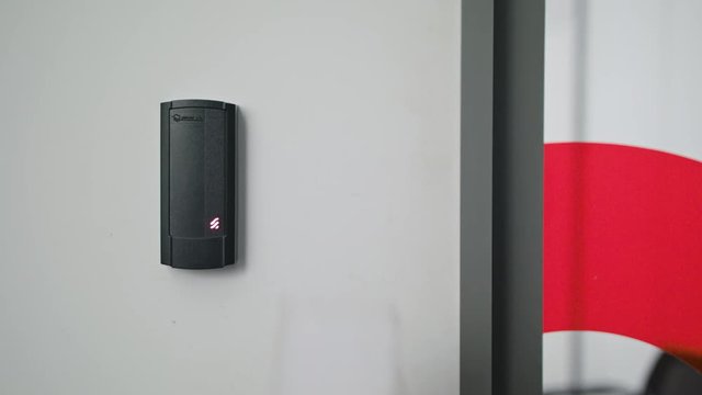 Close up of a woman using a modern intercom at a residential building entrance.