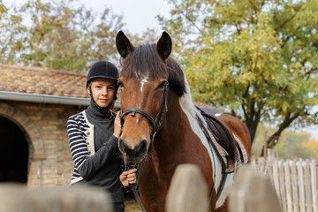 Fototapeta premium Ready for riding!-The girl holds her horse for reins