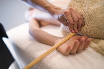 Massage therapist using wooden tool to massage patient