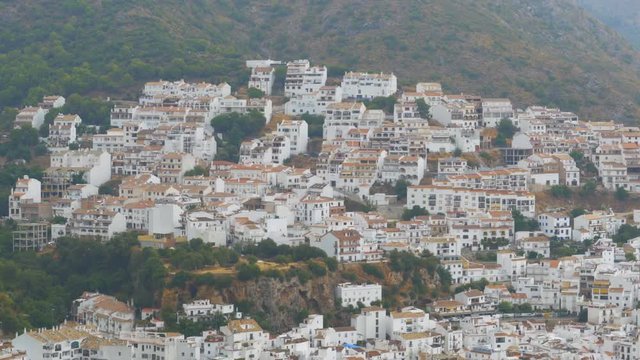 Spanish white village of Andalusia surrounded by mountains and trees. Panoramic view from above of a white city in the mountains of Spain.