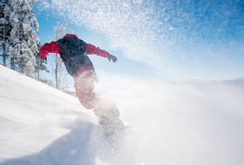 Horizontal low angle shot of a snowboarder riding the slope on a sunny winter day in the mountains....