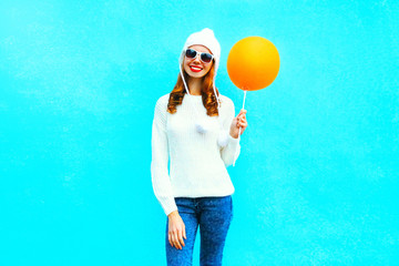 Beautiful young smiling woman with an orange air balloon on a blue background