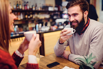 Beautiful couple drinking coffee talking and having fun in cafeteria