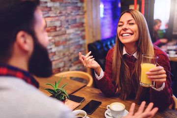 Beautiful couple drinking coffee talking and having fun in cafeteria