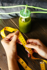 Healthy green detox for slimming down. Woman with measuring tape before drinking fruit and vegetables smoothie for weight loss. Dieting and fitness nutrition concept.