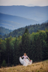 Bride runs along the hill with red wedding bouquet