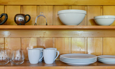 Fototapeta na wymiar Dishes, bowls, utensils, glasses on the wooden rack