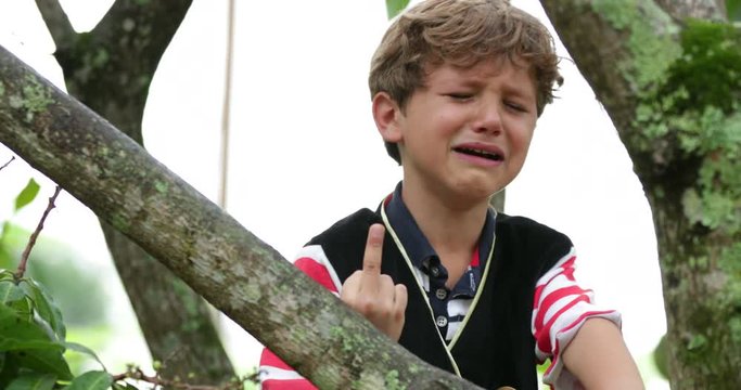 Crying infant child pointing the middle finger to camera. Inconsolable young boy cries while he gives the finger to viewer in a bashful candid manner in 4k