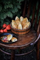 Russian patties with apples in a wooden tub on a wooden chair