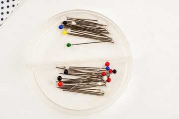 Needles for needlework in a plastic box on a white background, closeup shot