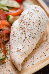 Closeup of boiled chicken breast with fresh vegetables, selective focus, vertical shot