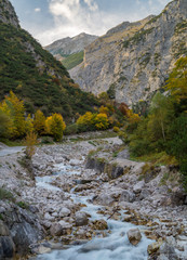 Fototapeta na wymiar View up a colorful valley in the alps during fall with a river flowing down.