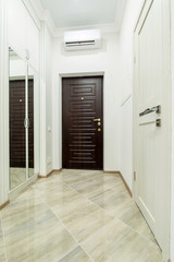 Apartment corridor overlooking an dark brown armored entrance door.
