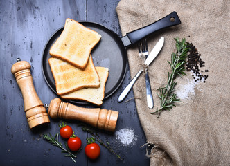 Fototapeta na wymiar Toasts on frying pan on grey background near sackcloth