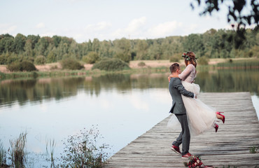 Bride and groom pose together before a beautiful lake in a sunny day