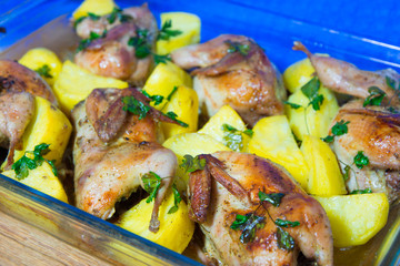 Quail meat baked in the oven. Freshly cooked quail with a side dish of new potatoes and parsley.