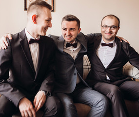 Groom and groomsmen sit on the couch in the room