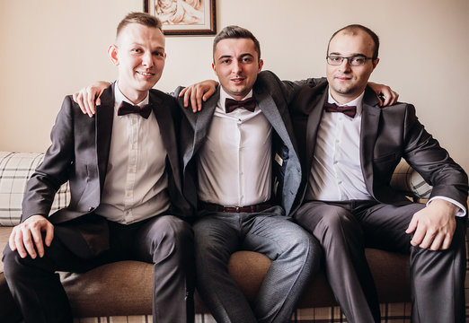 Groom and groomsmen sit on the couch in the room