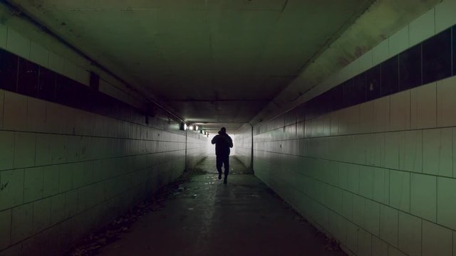 Young man is running along pedestrian subway tunnel. Sportsman is boxing in tunnel