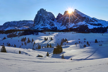 Winter sunrise on Alpe di Siusi with rising sun over Sassolungo and Sassopiatto, Dolomites, Italy - obrazy, fototapety, plakaty