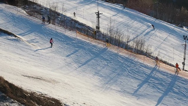 Training on the ski slope in the city. Active winter sports. People go down the hill on skis and snowboards. Active people are engaged in winter sports in the city