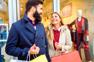Beautiful young loving couple carrying bags and enjoying together holiday shopping
