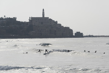 Tourists surfing in the beach with city in the background, Tel Aviv-Yafo, Tel Aviv, Israel