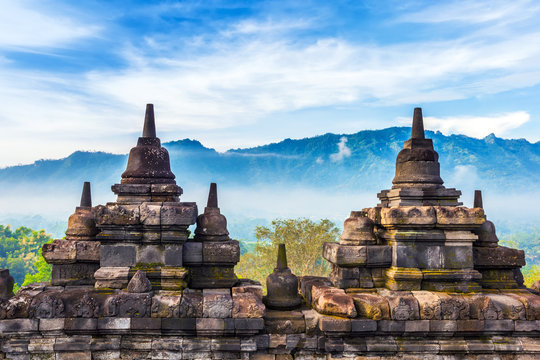 Candi Borobudur in the background of rainforest, morning mist and Sumbing Mountain. Borobudur, Yogyakarta, Jawa, Indonesia.