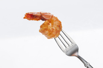 Cooked shrimps on ss fork on white background 