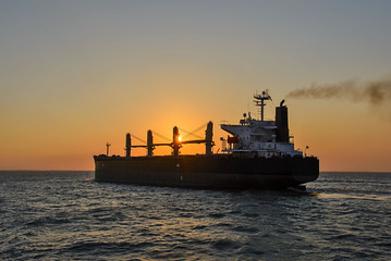 Obraz premium Bulker cargo vessel at sunset