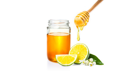 honey dipper with honey dripping down, honey jar, and cut fresh lime on isolated white background