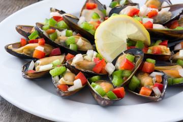 Steamed mussels with peppers and onion on wooden table

