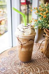 Ice mocha frappe served with whipping cream in plastic cup. Cafe view.