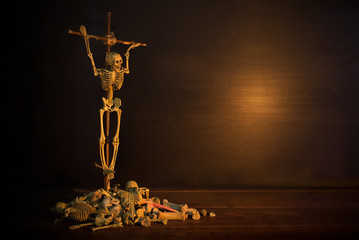 Crucifixion wooden skeleton top on pile of bone by god of death because perpetration of a sin