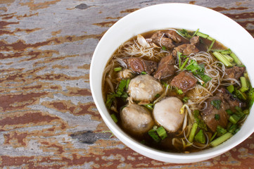 Meat Noodle. Thin rice noodle with Stewed Beef and meat ball. Top view on wooden table with copy...