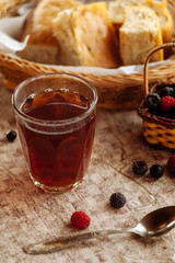 Berries in a basket, roll and tea on the table. Breakfast.