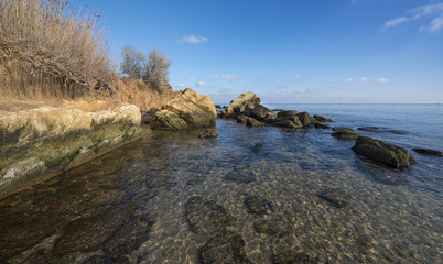 Fototapeta na wymiar Beautiful seaside and many stones in trasparent water in sunny day