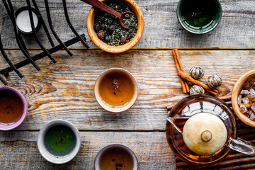 Obraz na płótnie Canvas Tea ceremony concept. Tea pot, cups, dry tea leaves, sugar on rustic wooden background top view
