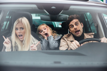 Shocked man sitting in car with his wife and daughter