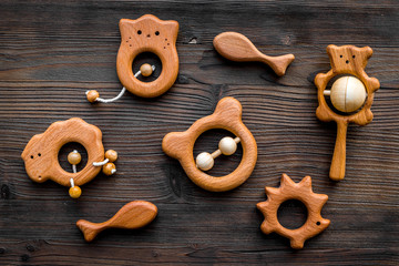 Cute wooden handmade toys for newborn on dark wooden background top view