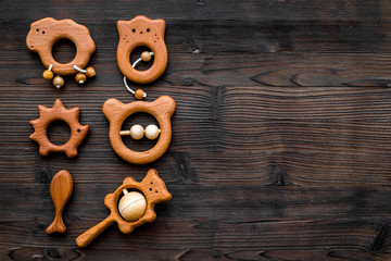 Cute wooden handmade toys for newborn on dark wooden background top view copyspace