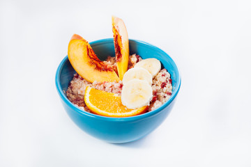Naklejka na ściany i meble Oat porridge in a bowl, with orange and banana. On a white background.