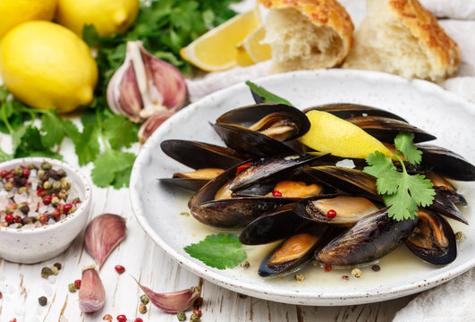 Delicious mussels in white wine with lemon, garlic, herbs and spices. Cilantro and pepper. Seafood. Clams in the shells. Snack for gourmets. Selective focus
