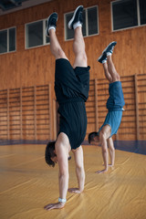 two guys walking on hands in oldschool gym;