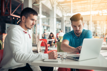 two handsome guys planning in cafe;