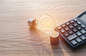 Energy saving light bulb with stacks of coins and calculator for financial, accounting and saving...